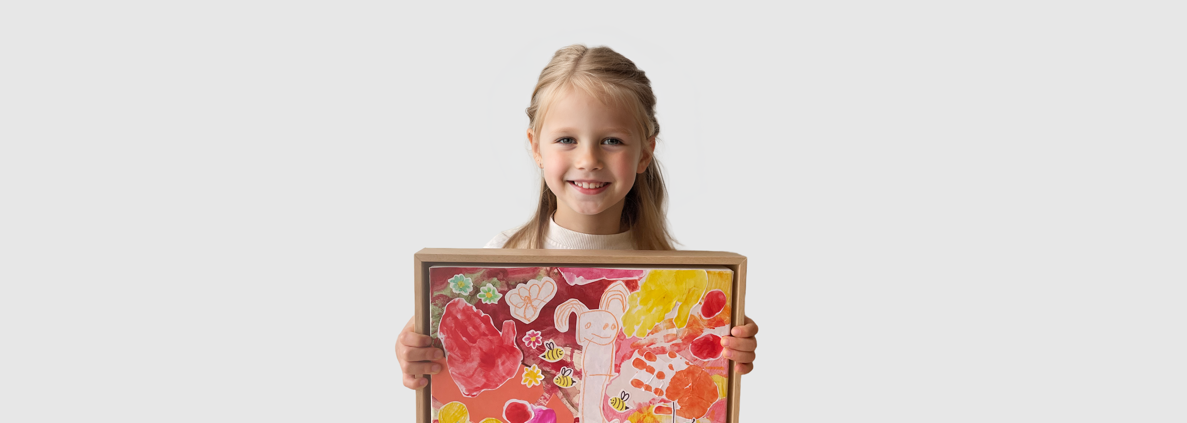 A child holding a framed piece of colourful artwork