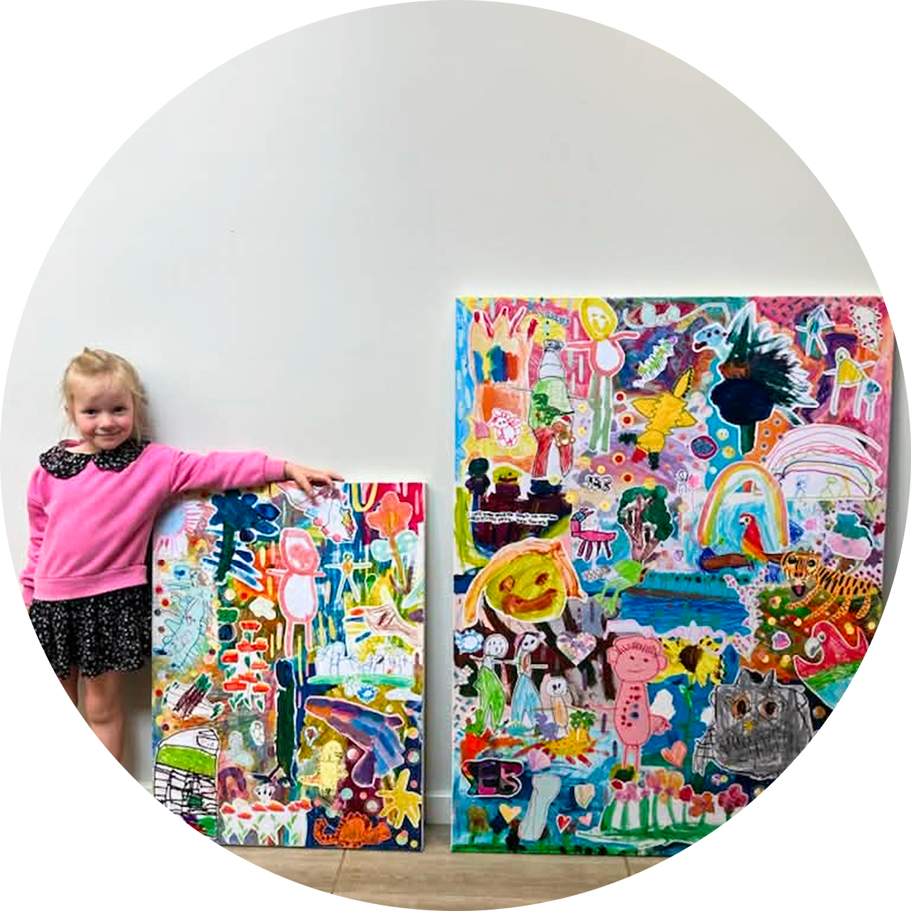 A child proudly standing beside two finished collage artworks